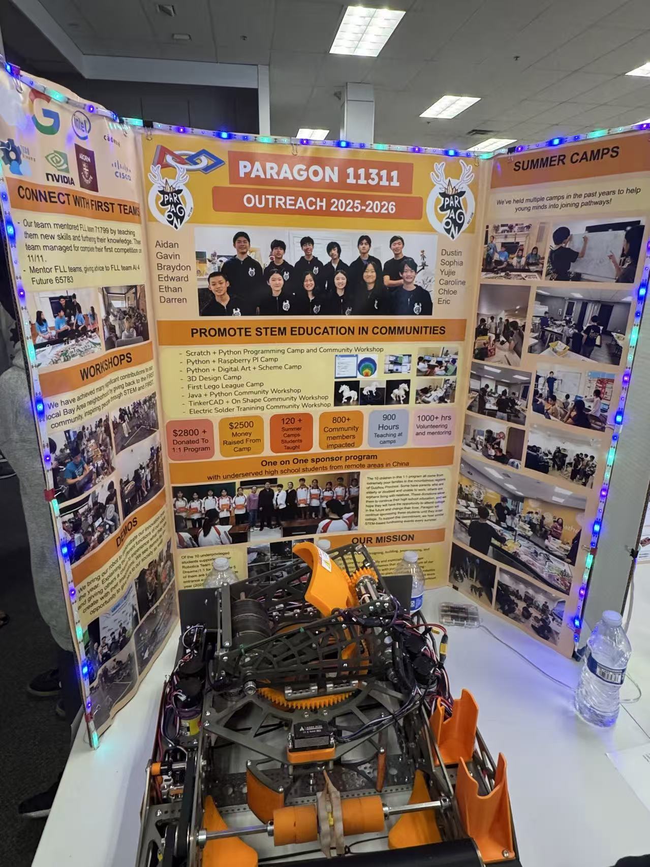 Paragon robot on a table in front of the team's illuminated outreach display